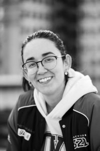 Black and white portrait of a happy woman wearing glasses and a hoodie.